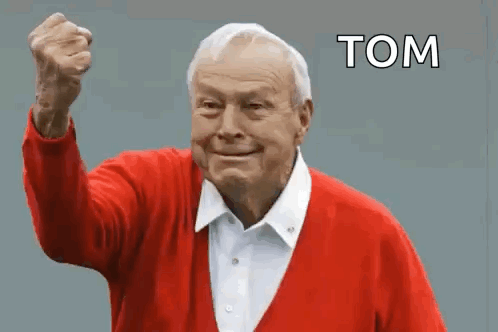 An Elderly Man In A Red Sweater Is Holding His Fist Up In The Air And Says Tom . GIF