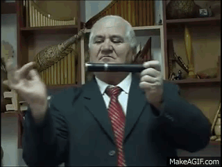 An Elderly Man In A Suit And Tie Is Holding A Pipe In His Hands . GIF