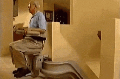 An Elderly Man Is Sitting In A Chair On A Set Of Stairs . GIF