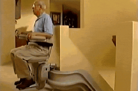 An Elderly Man Is Sitting In A Chair On A Stair Lift . GIF
