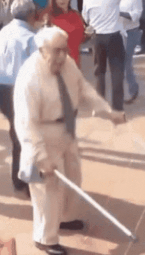 An Elderly Man With A Cane Is Dancing In A Crowd GIF