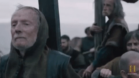 an elderly man with a hood on his head is sitting on a boat with other men .