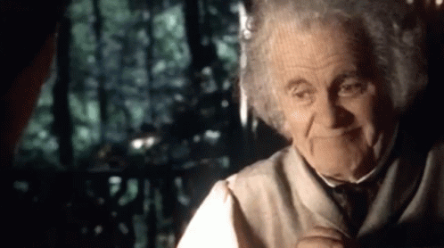 An Elderly Man With Curly Hair Is Smiling While Talking To Another Man In A Dark Room . GIF