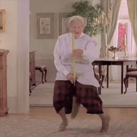 An Elderly Woman Is Dancing In A Living Room With A Yellow Stick GIF
