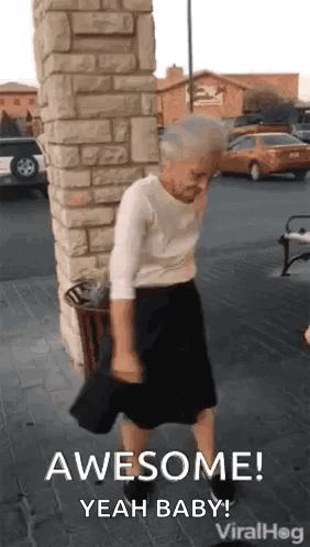 An Elderly Woman Is Dancing In Front Of A Brick Wall And A Trash Can . GIF
