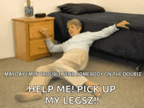 An Elderly Woman Is Laying On The Floor In Front Of A Bed Asking For Help GIF
