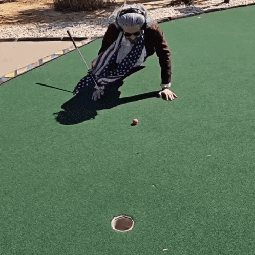 An Elderly Woman Is Playing A Game Of Golf On A Green GIF