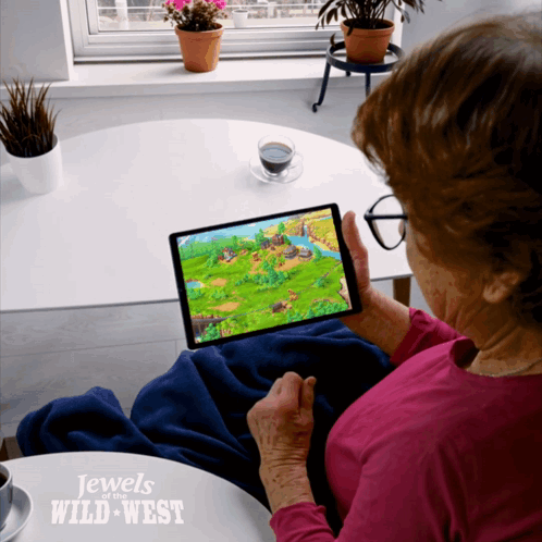 An Elderly Woman Is Playing A Game On A Tablet With The Words Jewels Of The Wild West On The Bottom GIF