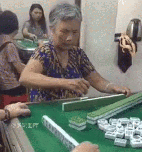 An Elderly Woman Is Playing Mahjong On A Green Table . GIF
