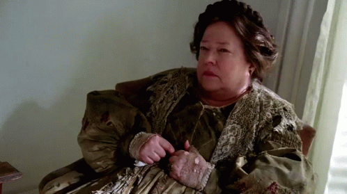 An Elderly Woman Is Sitting In A Chair With Her Hands On Her Stomach . GIF