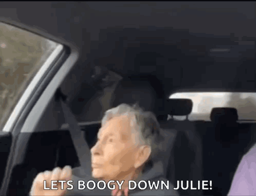 an elderly woman is sitting in the back seat of a car and shouting .