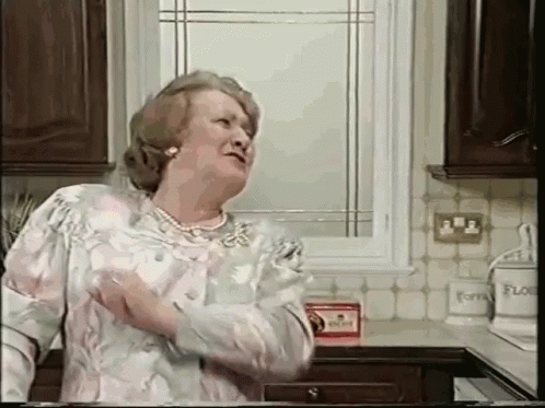 An Elderly Woman Is Standing In A Kitchen With A Box Of Flour On The Counter GIF
