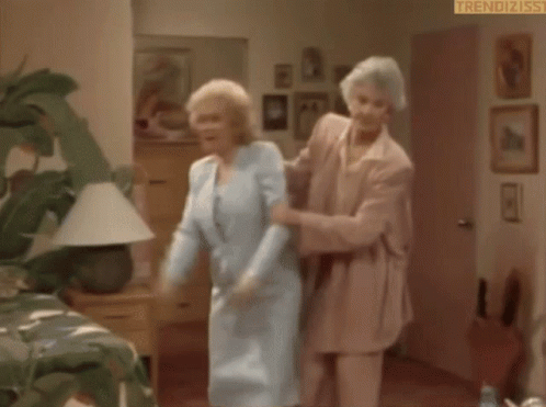 an elderly woman is standing in a room holding a door open .