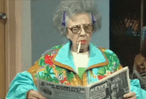 An Elderly Woman Smoking A Cigarette While Reading A Newspaper . GIF