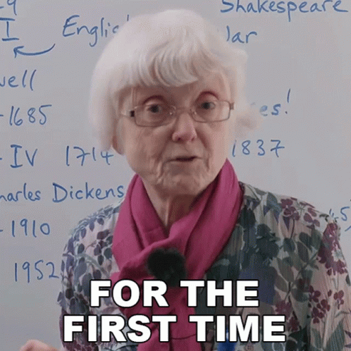 An Elderly Woman Stands In Front Of A White Board With The Words " For The First Time " Written On It GIF