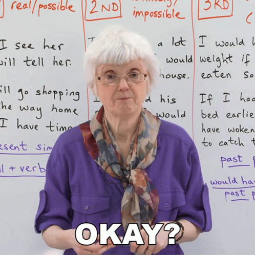 An Elderly Woman Stands In Front Of A Whiteboard With Okay Written On It GIF
