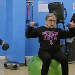 An Elderly Woman Wearing A Super Diva Shirt Is Sitting On A Green Exercise Ball GIF