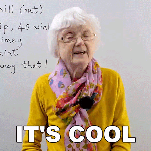 An Elderly Woman Wearing Glasses And A Scarf Says It 'S Cool In Front Of A White Board GIF