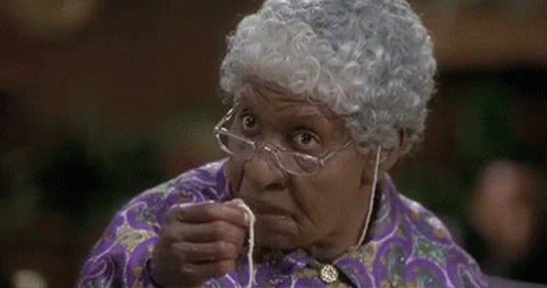 An Elderly Woman Wearing Glasses And A Wig Is Holding A Piece Of String In Her Hand . GIF