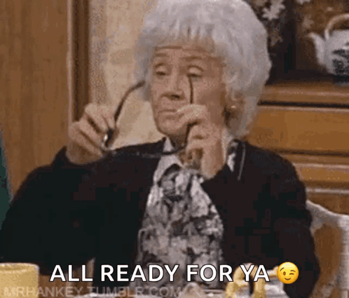 An Elderly Woman Wearing Glasses Is Sitting At A Table With The Words All Ready For Ya GIF
