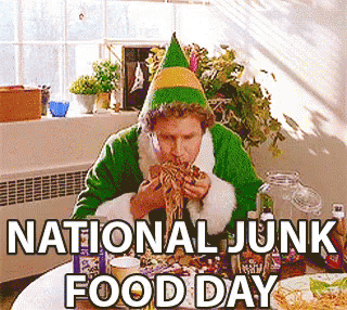 An Elf Is Sitting At A Table Eating Food On National Junk Food Day GIF