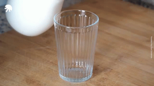 An Empty Glass Sits On A Wooden Table With A White Arrow Pointing Up GIF