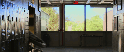 An Empty Hallway With A Red Exit Sign Above The Window GIF
