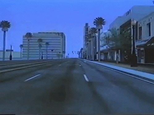 An Empty Street With Palm Trees And A Building That Says ' Tnt ' On It GIF