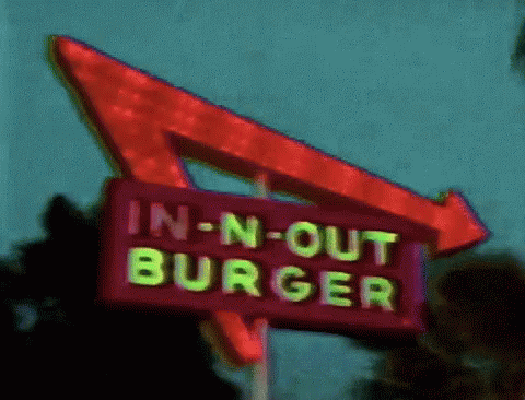 An In-N-Out Burger Sign With A Red Arrow GIF