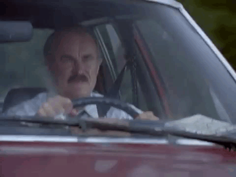 An Old Man Is Driving A Car And Giving The Middle Finger . GIF