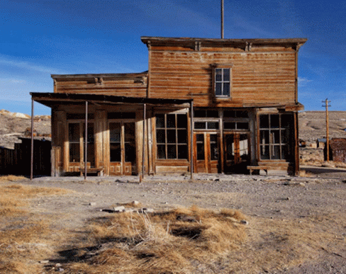 An Old Wooden Building In The Desert With A Blue Sky In The Background GIF
