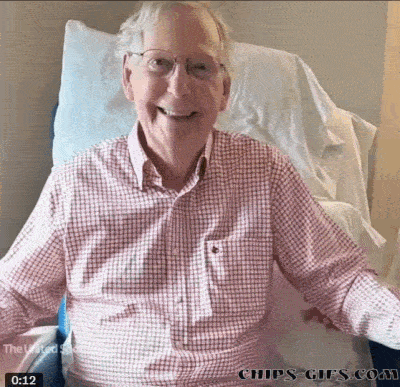 An Older Man In A Plaid Shirt Is Sitting In A Hospital Bed GIF