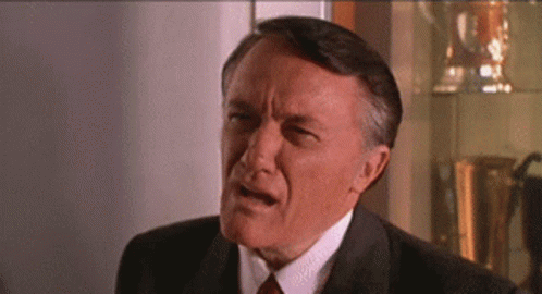 An Older Man In A Suit And Tie Is Making A Funny Face GIF