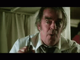 An Older Man In A White Shirt And Tie Is Holding A Pair Of Scissors . GIF