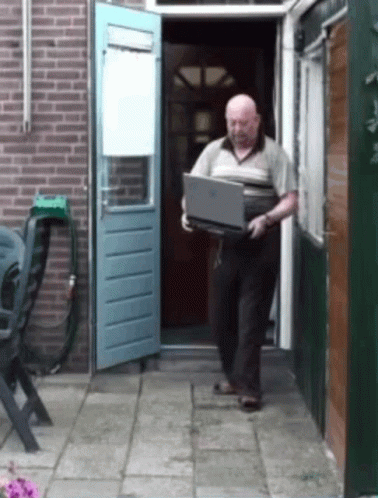 An Older Man Is Carrying A Laptop Out Of A House GIF