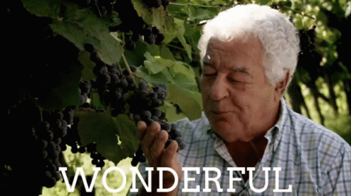 An Older Man Smelling A Bunch Of Grapes With The Word Wonderful Written Below Him GIF