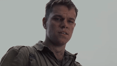 An Older Man Wearing A White Shirt And A Grey Jacket Looks At The Camera GIF