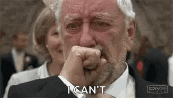 An Older Man With A Beard Is Crying And Covering His Mouth With His Hand . GIF