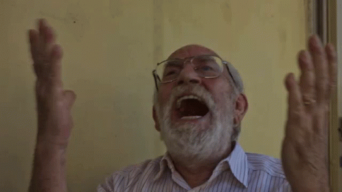 An Older Man With Glasses And A Beard Is Screaming With His Mouth Open GIF