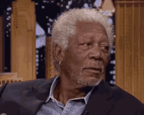 An Older Man With Gray Hair And A Beard Is Sitting In A Chair . GIF