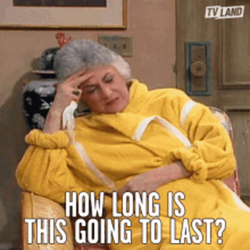 An Older Woman In A Yellow Robe Is Sitting In A Chair With The Caption How Long Is This Going To Last GIF