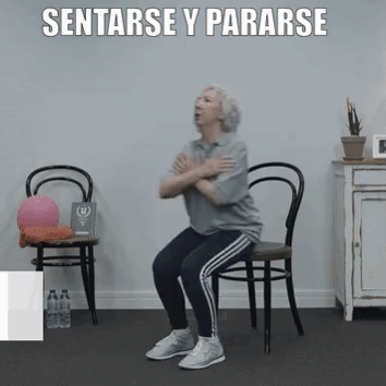 An Older Woman Is Squatting On A Chair With Her Arms Crossed . GIF