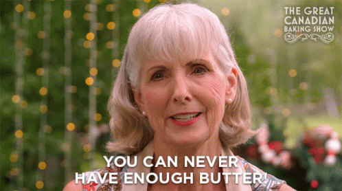 An Older Woman Says " You Can Never Have Enough Butter " In Front Of A Sign For The Great Canadian Baking Show GIF
