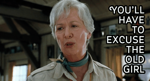 An Older Woman Says You 'Ll Have To Excuse The Old Girl While Wearing A Scarf Around Her Neck GIF