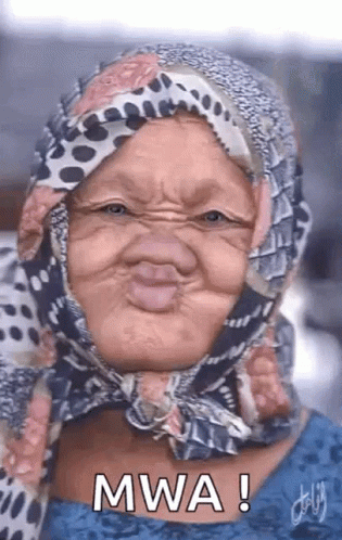 An Older Woman Wearing A Scarf Around Her Head Is Making A Funny Face . GIF