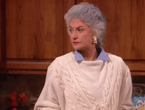 An Older Woman With Gray Hair Wearing A White Sweater GIF