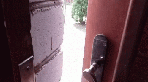 An Open Door With A Brick Wall Behind It And A Door Handle GIF