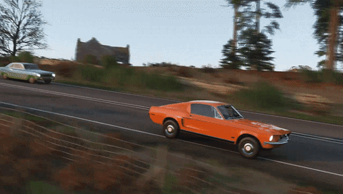 an orange mustang is driving down a road next to a white mustang