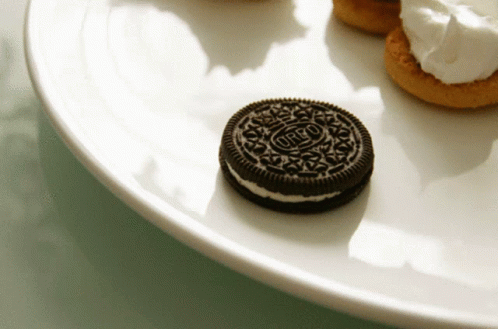 An Oreo Cookie Sits On A White Plate With Other Cookies GIF
