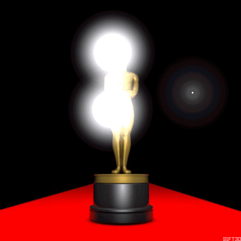 An Oscar Statue Is On A Red Carpet With A Light Behind It GIF